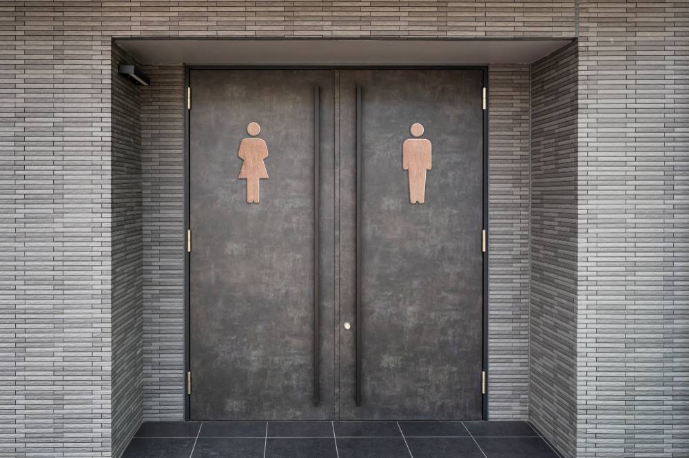 Női és férfi mosdó bejárati ajtói egymás mellett, piktogramokkal jelölve – közösségi mosdóhigiéniai környezet.